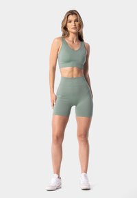 Lichtgroene sportoutfit bestaande uit een cropped tanktop met een ronde hals en high-waisted shorts, gemaakt van een gladde, elastische stof.