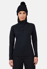 Maglione nero a maniche lunghe con zip a quarto realizzato in tessuto elastico, dotato di un alto colletto e spalle senza cuciture, abbinato a un berretto in maglia nera con pompon.