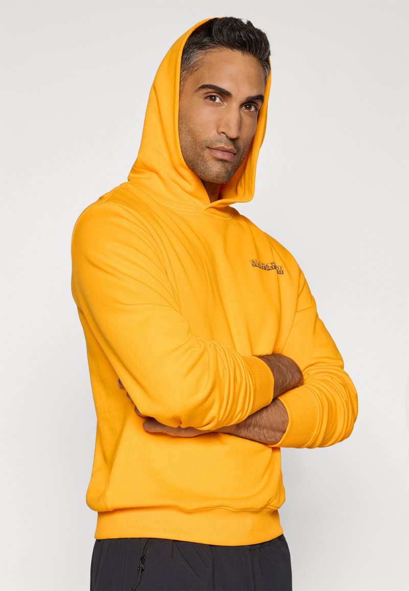 Gelbe Kapuzenjacke mit gerippten Bündchen und Saum. Besitzt ein kleines Logo auf der Brust. Weicher Stoff, lässige Passform.