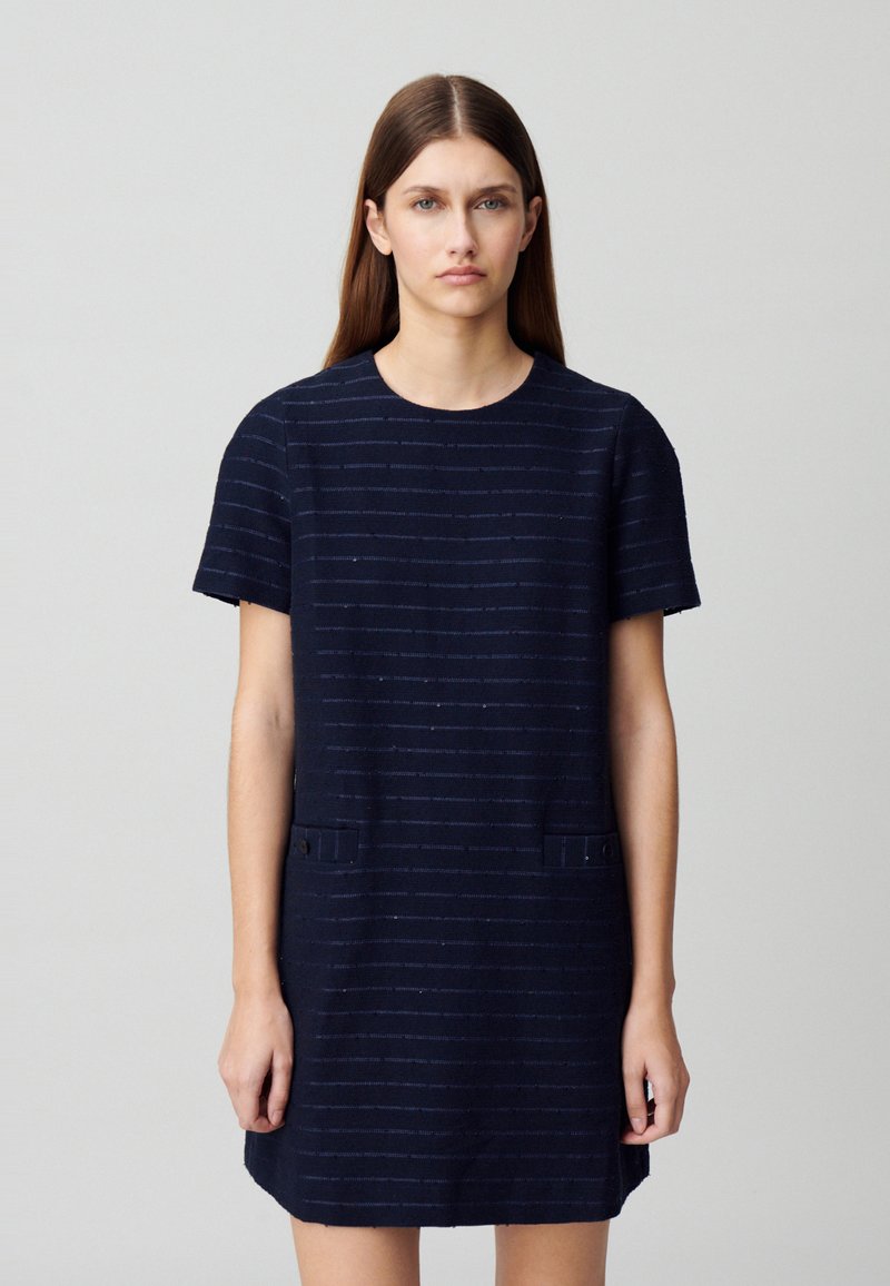 Vestido de marina de manga corta con rayas horizontales, que presenta dos bolsillos frontales y un escote redondo. Tejido texturizado con detalles sutiles.