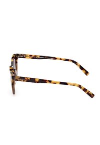 Gafas de sol de carey con gruesos marcos rectangulares, fabricadas con plástico bio-based. Presentan patas delgadas con una textura suave y un branding sutil.