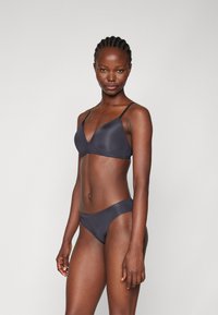 Mørk grå undertøysett med en trekantet bralette og matchende bikinitruse. Stoffet er glatt med minimale sømmer og justerbare stropper.