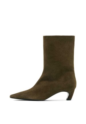 Stivaletto alla caviglia in camoscio marrone con punta a punta e tacco medio. Presenta una texture liscia e un design elegante e minimalista.