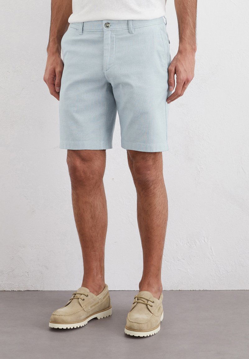 Shorts bleu clair en tissu texturé, dotés d'une fermeture à bouton à l'avant, de poches latérales et d'une coupe droite.