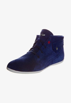 Námořnické modré semišové kotníkové boty s textura povrchem, černými tkaničkami, červeným akcentem a stříbrným logem na jazyku. Bílá gumová podrážka.