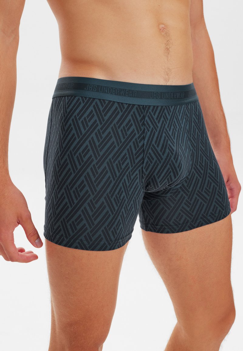 Sorte boxershorts med et geometrisk mønster, med en solid linning mærket "JBS Underwear." Materialet ser glat og tætsiddende ud.