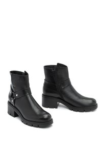 Mustat nahkaiset nilkkasaappaat, joissa on pyöristetty kärki, vetoketjukiinnitys ja koristeellinen hihna, jossa on hopeanvärisiä yksityiskohtia. Tukevat korkokengät.