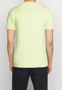 Světle žluté tričko s krátkým rukávem vyrobené z měkké bavlny, s klasickým výstřihem a rovním lemem, s hladkým povrchem.