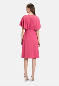 Rosenrotes Kleid mit einem schwingenden Ärmel-Design, Taillennaht und einem Schlüssellochverschluss im Rücken. Sanfte Textur und knielanger Schnitt.