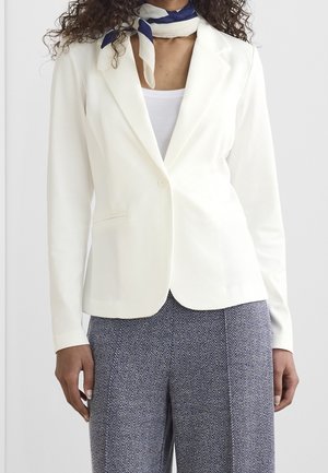 Blazer bianco su misura con chiusura a un bottone, revers a punta e tasche laterali, abbinato a pantaloni a righe blu e bianchi.