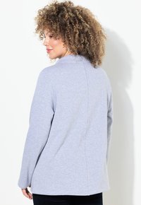 Top gris de manga larga hecho de una tela suave, con un cuello tipo mock y una costura trasera recta, con un ajuste relajado y una textura suave.