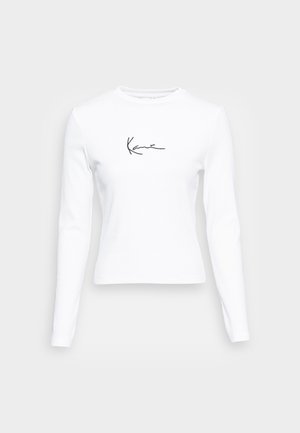 White long-sleeve t-shirt made of ribbed fabric featuring a subtle black signature design on the front. Round neckline, fitted shape.