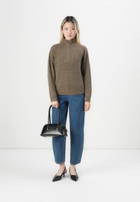 Maglione a zip in maglia marrone, vestibilità ampia; jeans blu a vita alta; borsa in pelle nera con manici corti; décolleté neri a punta.