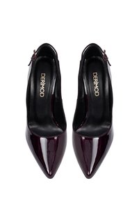 Tacones de charol de color burdeos profundo, con punta afilada, diseño de tirantes traseros y un pequeño acento de cremallera. Interior negro texturizado.