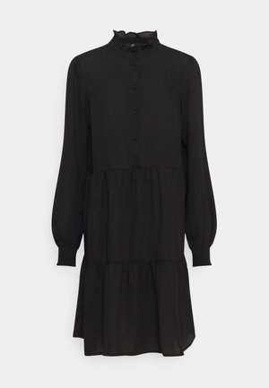 Czarna sukienka z długim rękawem, z falbanami na plisowanej spódnicy, wysokim kołnierzem z falbankami, zapięciem na guziki z przodu i elastycznymi mankietami.