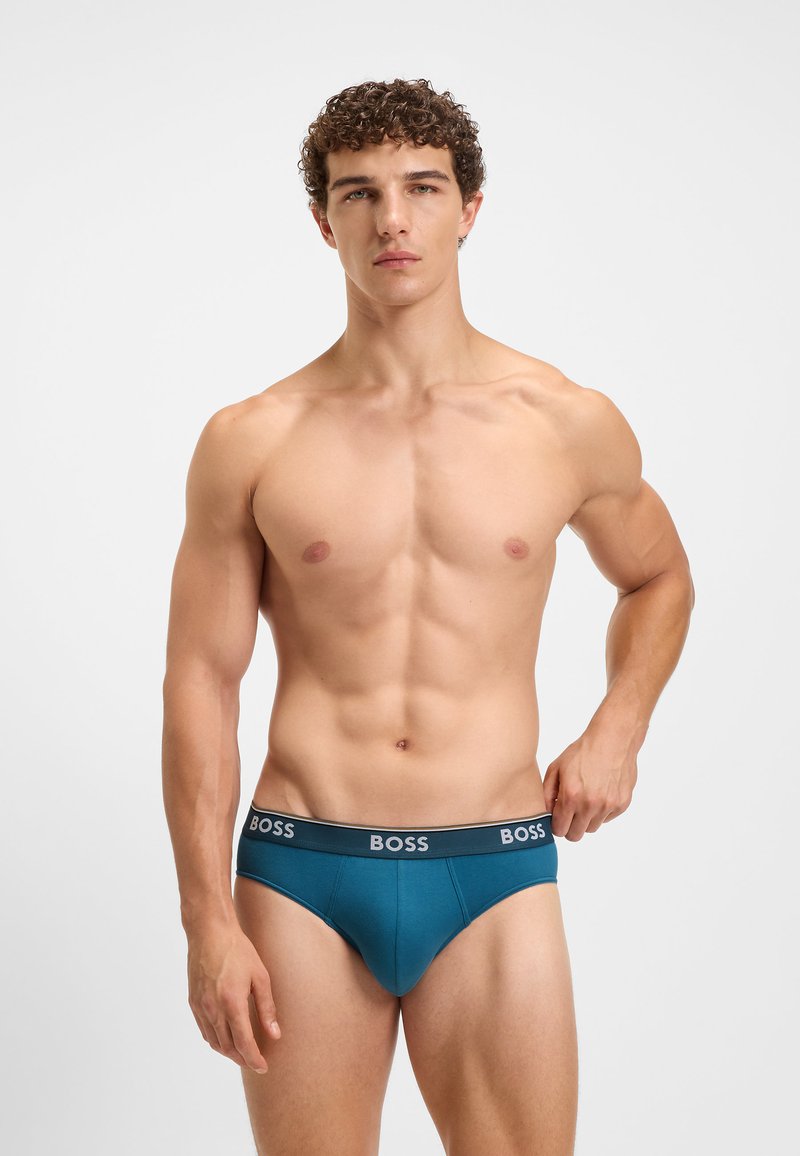 Chiloți din bumbac de culoare teal, cu un band elastic gri inscripționat cu logo-ul 'BOSS'. Design ajustat, cu o textură netedă și fără modele vizibile.