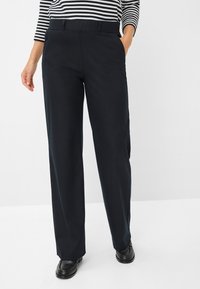 Marineblauwe wijde broek met een gladde stof, met een voorkant van de tailleband en zijzakken, gecombineerd met zwarte instap schoenen.