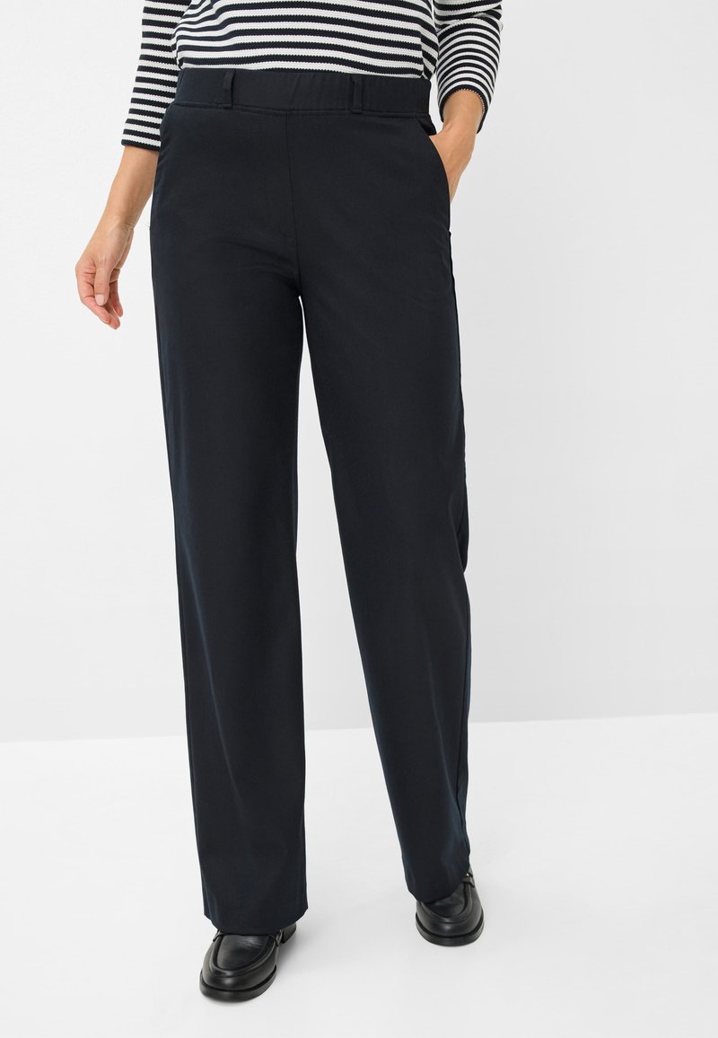 Marineblauwe wijde broek met een gladde stof, met een voorkant van de tailleband en zijzakken, gecombineerd met zwarte instap schoenen.