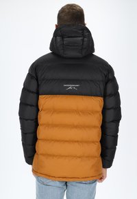 Fodrad jacka med en svart övre del och en orange undre del. Har en huva och "SWEDEMOUNT"-logotypen på baksidan.