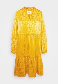 Gul klänning med lång ärm, en skålad krage, lager-på-lager design och glänsande leopardmönster. Tillverkad av ett glansigt material, knälång.