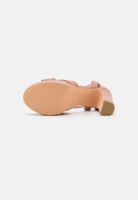 Sandale à talons rose blush avec une tige en simili cuir lisse, une large sangle sur le pied et une semelle en caoutchouc texturée pour une meilleure adhérence.