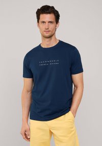 Camiseta de algodón azul marino con cuello redondo y mangas cortas. Presenta un texto en blanco que dice "FACONNABLE FRENCH RIVIERA" en el frente.