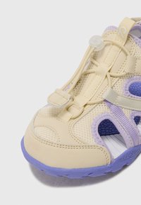 Beige und lavendel Farbiger sportlicher Sandale mit Mesh-Obermaterial, Gummisohle, verstellbarem elastischem Schnürsystem und Aussparungen an den Seiten.