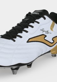 Λευκό και μαύρο παπούτσι ποδοσφαίρου με χρυσές λεπτομέρειες, μαύρα κορδόνια, μεταλλικά στράντζα και λογότυπο "Aquila Cup" στο πλάι.