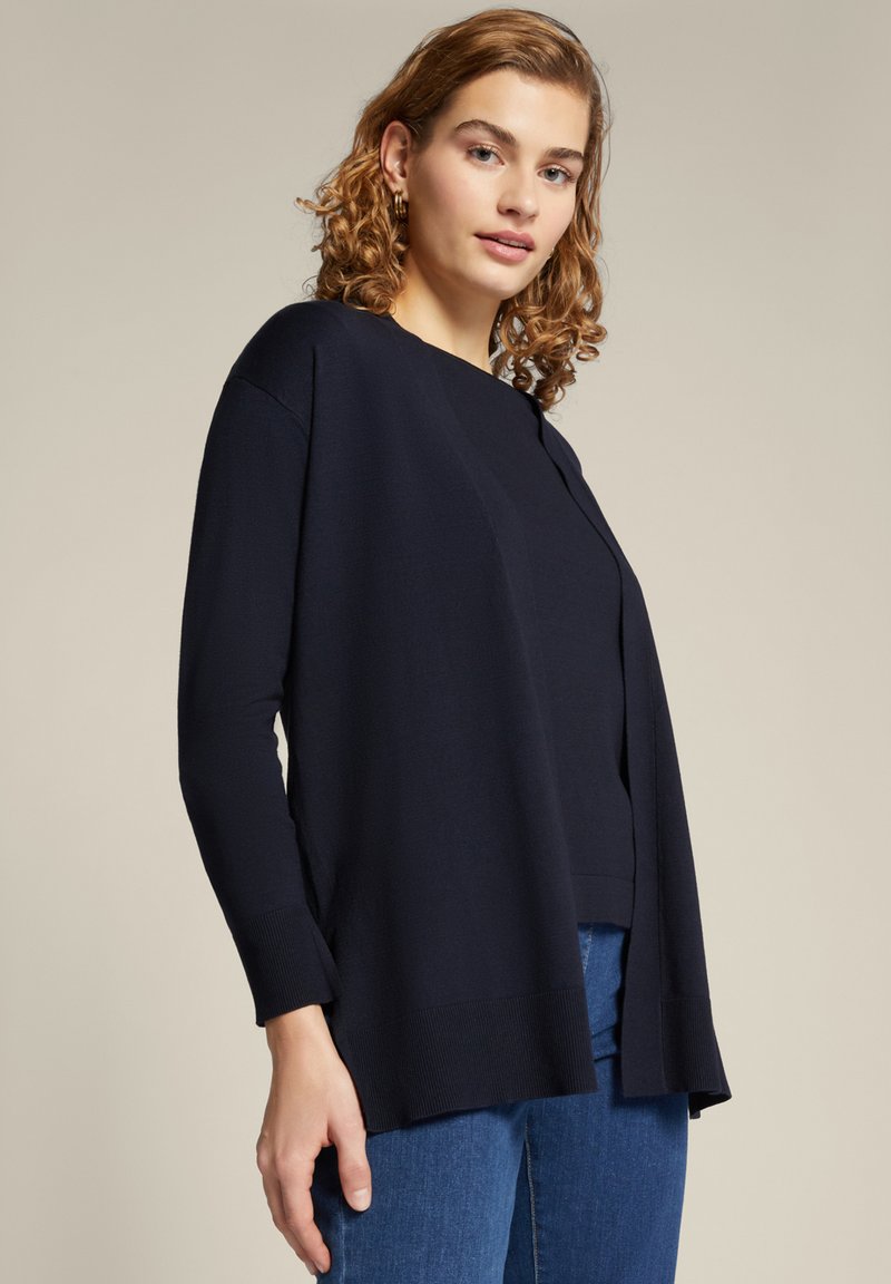Cardigan blu navy realizzato in morbido tessuto a maglia, dotato di maniche lunghe, apertura frontale e orlo a coste per un ulteriore tocco di texture.