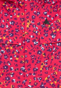 Giacca di un brillante rosso con stampa leopardata viola, gialla e bianca, due tasche frontali e logo Burton in nero sul petto.