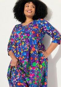 Vestido morado vibrante con escote redondo y mangas tres cuartos, que presenta un patrón circular colorido y bolsillos laterales.