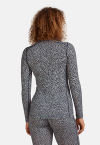 Long-sleeve athletic top featuring a black and white pattern, fitted design, smooth texture, and contrasting seams. Ideal for active wear.