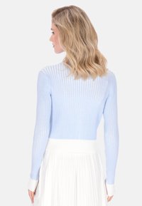 Jasnoniebieski prążkowany sweter z długimi rękawami i białym pasem w talii. Tkanina wydaje się miękka i lekka, a krój dopasowany.