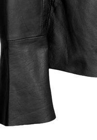 Mustan nahkatakin hiha, jossa on sileä pinta, rakenteellinen muotoilu ja kevyt levennys hihansuussa näkyvillä ompeluilla.