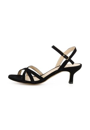 Schwarze Veloursleder-Sandale mit kleinem Absatz, gekreuzten Riemen über den Zehen und einem Knöchelriemen mit goldener Schnalle vor weißem Hintergrund.