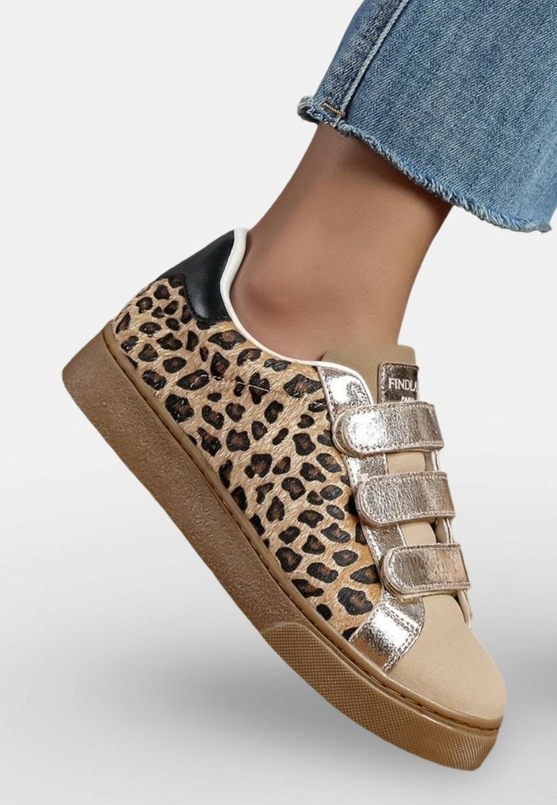 Baskets à imprimé léopard beige avec des straps Velcro métalliques dorés, accent noir au talon et semelles en caoutchouc. Détail texturé de l'imprimé animal.