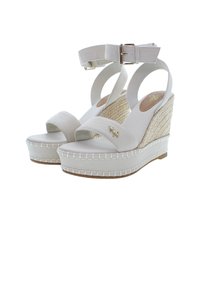 Bílé klínové sandály s plátěnými pásky, tkanou jútovou patou a sponou na zapínání. Hladký povrch se šitím podél základny.