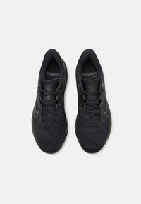 Des chaussures de course noires avec une tige en maille texturée, des lacets plats et des semelles rembourrées. Subtiles accents de logo gris sur les côtés.