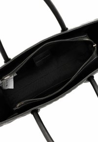 Black leather handbag interior with a zippered pocket, fabric lining, and dual handles. Features minimalist design and smooth texture.
