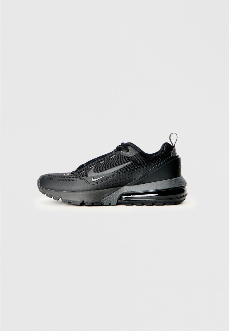 Zapatilla deportiva negra de Nike fabricada con materiales de malla y sintéticos, presenta una puntera redondeada, suela acolchada y una unidad de aire visible en el talón.