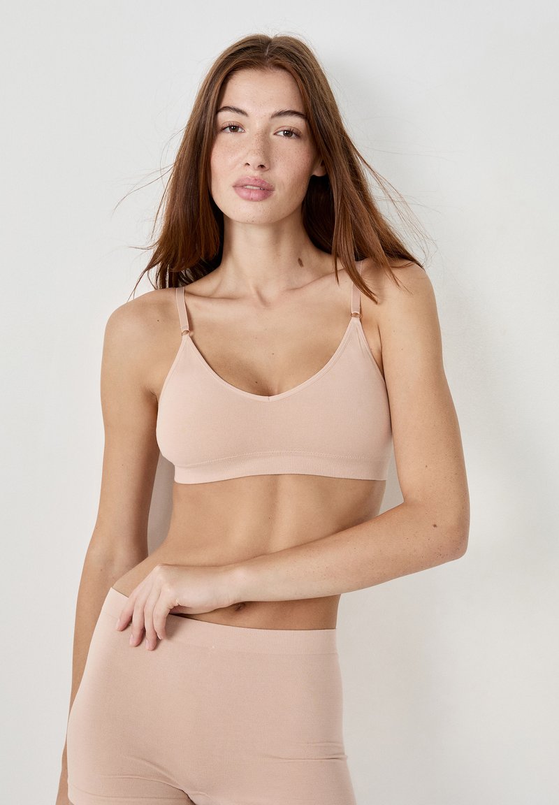 Bralette nude sin costuras con tirantes ajustables, tela suave y un ajuste cómodo, combinado con shorts nude sin costuras a juego.