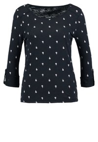 T-shirt à manches longues bleu marine en tissu doux, arborant un motif répété de petits voiliers blancs et des poignets à retrousser.