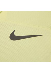 Nike Sportshirt in Hellgelb mit schwarzem Swoosh-Logo. Der Stoff hat eine strukturierte, atmungsaktive Oberfläche. Minimale Nähte sichtbar.