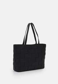 Zwarte geweven tote bag met twee textuur-geflatste handvatten. Heeft een rechthoekige vorm en een strakke, minimalistische uitstraling.