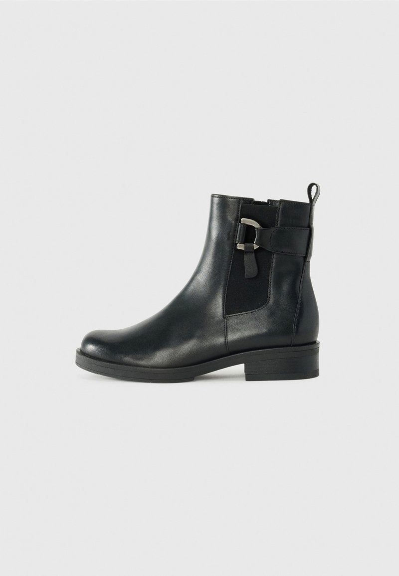 Bottine en cuir noir avec petit talon, bride à boucle latérale, panneau élastique et languette de traction sur fond gris.