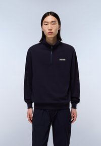 Suéter navy con cuello alto, cierre de cremallera y puños acanalados. Presenta un pequeño logo blanco en el pecho, hecho de una tela suave.