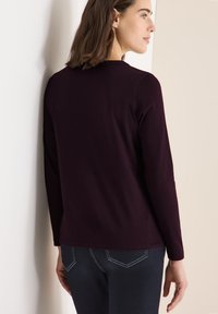 Langsleeve top in diep bordeauxkleurige katoenmix, met een ronde halslijn en een ontspannen pasvorm. Draag het met donkere jeans met contrasterende stiksels.