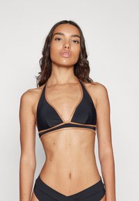 Black bikini top with a halter design, featuring gold accents along the edges. Smooth fabric, triangular cups, and a simple closure.