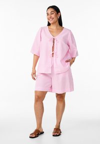 Pink and white striped short-sleeve top with a V-neck and tie detail, paired with matching shorts. Features pockets and a relaxed fit.