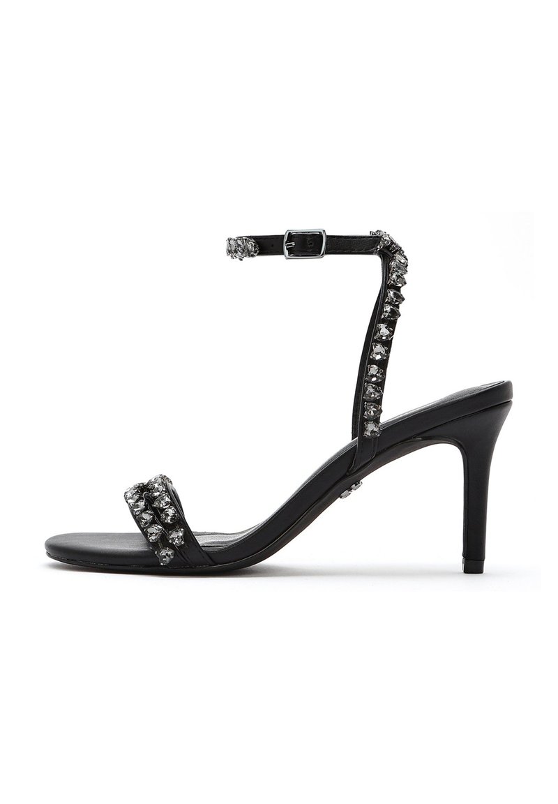 Las sandalias de tacón alto negras tienen un acabado brillante, dos correas decoradas con strass y una correa para el tobillo con una hebilla de metal.